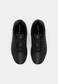 Een paar zwarte Calvin Klein Jeans sneakers met veters, bovenaan bekeken op een witte achtergrond.
