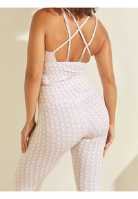Ensemble de vêtements de sport rose clair avec un haut à motifs doté de bretelles croisées et un legging ajusté au toucher doux.