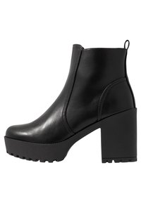 Mustat nilkkurit, jotka on valmistettu sileästä nahasta, ja niissä on paksu pohja ja blokkikanta, sivuvetoketju ja vähäiset ompelutiedot.