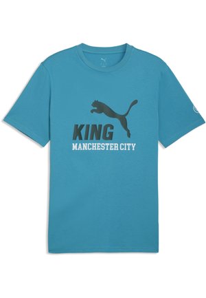 Niebieska koszulka Puma z krótkim rękawem z napisem "KING MANCHESTER CITY" oraz czarnym logo puma skaczącej z przodu.