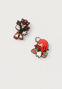 Kaks kummist nööpnõela, millel on multikategelased. Üks on musta ja punase värvusega, piiklevate juustega, teine punane, pikkade juuste ja roheliste detailidega.