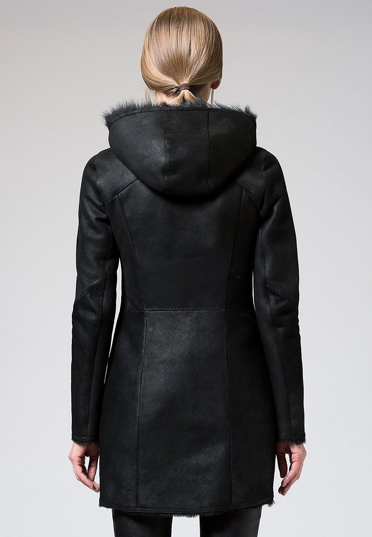 Manteau en cuir noir au design ajusté, avec capuche bordée de fourrure et accents cousus. Texture lisse, coupe mi-longue, adapté aux temps frais.
