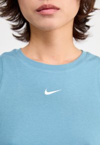 Light blue ribbed tank top made of cotton with a round neckline and a small white Nike swoosh logo on the chest.