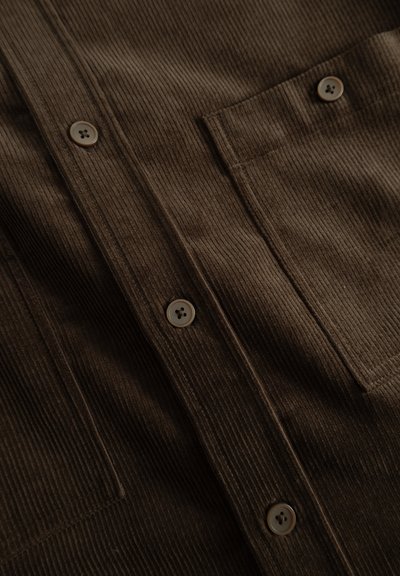 Brown corduroy shirt featuring a button-down front, textured fabric, two pockets, and five buttons.