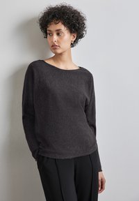 Dunkelgrauer Langarmpullover mit weitem Halsausschnitt und geripptem Design, kombiniert mit schwarzen Hosen. Schlichte und lockere Passform ohne Muster.