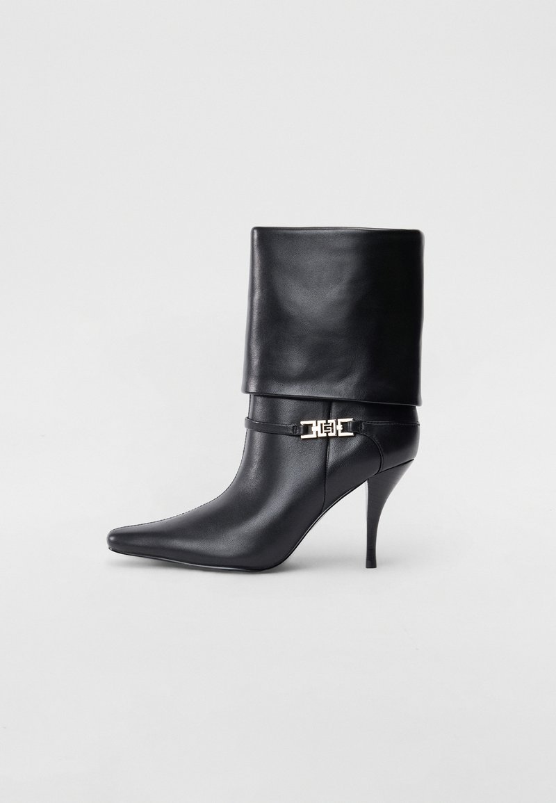 Sort læder ankelstøvle med spids tå, høj stiletto hæl, fold-over manchet og en guld dekoreret spænde detalje på anklen.