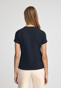 Camiseta negra de manga corta con un escote redondo, textura suave, diseño ajustado y una parte trasera sencilla sin adornos ni patrones.