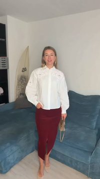 Fehér blúz hímzett díszítéssel, hosszú ujjú, bordó, testhezálló ceruzaszoknyával, elöl sliccel. Bézs cipő és kézitáska.