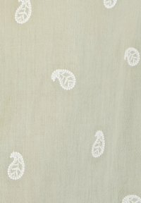 Tela bordada con un fondo verde claro y patrones de paisley blancos, mostrando una textura fina y un detallado delicado.