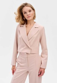 Geknipt blush-coloured blazer met een gelapte kraag, dubbele knoopsluiting en lange mouwen, gecombineerd met bijpassende fitted pantalon. Soepele textuur.