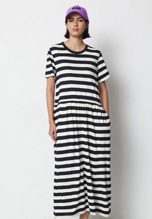 Gestreiftes Baumwollkleid mit marineblauen und weißen horizontalen Streifen, kurzen Ärmeln, elastischem Bund und Seitentaschen. Mit einer lila Kappe kombiniert.