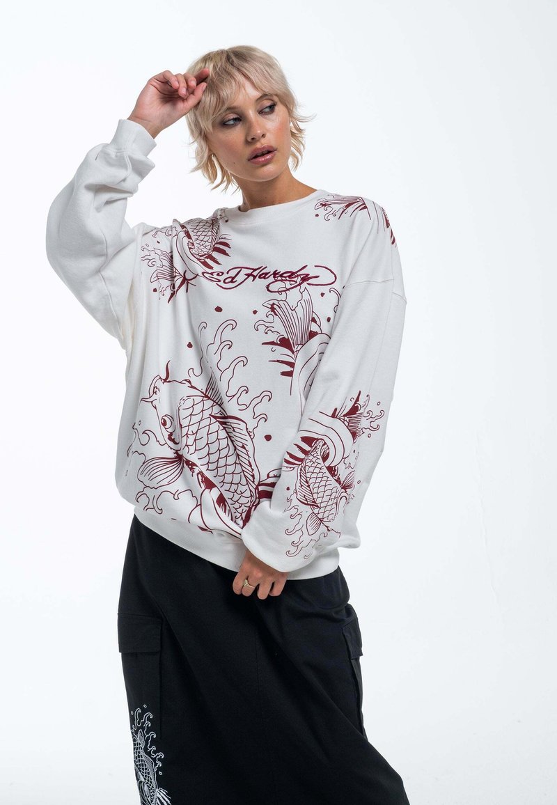 Witte sweatshirt met rode koi-vissen en golfontwerpen. Het kledingstuk heeft een ontspannen pasvorm met lange mouwen en geribbelde manchetten.