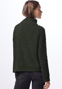 Maglione verde scuro con colletto alto, texture a costine, vestibilità rilassata e spacchetti laterali. Materiale in misto cotone.