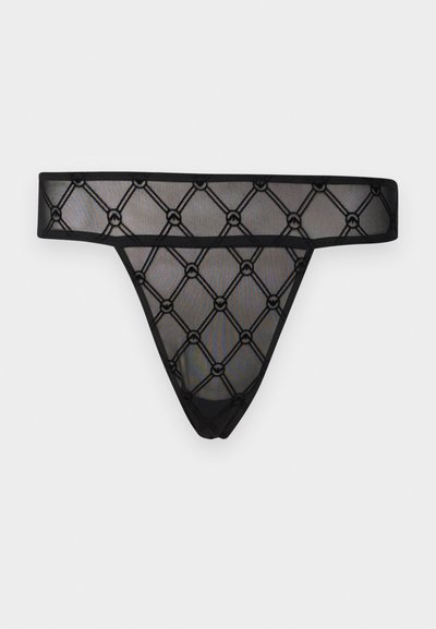 String noir en maille avec un motif en diamant et des accents circulaires. La taille lisse et la texture translucide rehaussent son design.