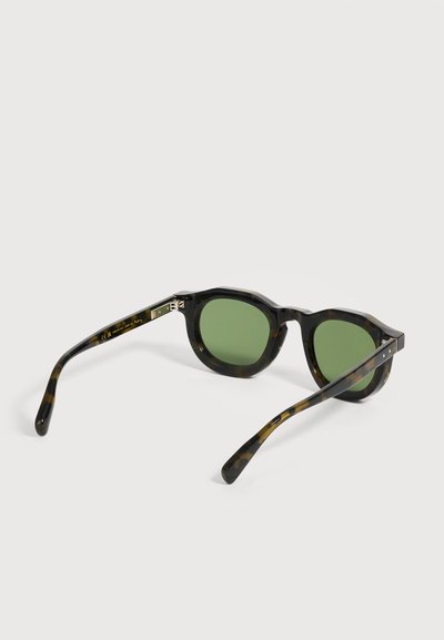 Lunettes de soleil noires et écaille avec des verres verts, vues de l'arrière sur fond blanc.