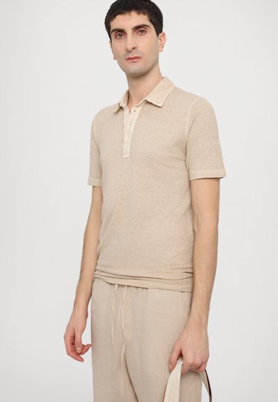 Polo de color beige con mangas cortas y cuello tipo polo, con una tela texturizada y una fila de botones de color claro.