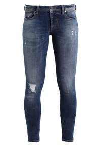 Jeans ajustados de denim azul, con un lavado desgastado, detalles desgastados y un cierre con cremallera y botón.