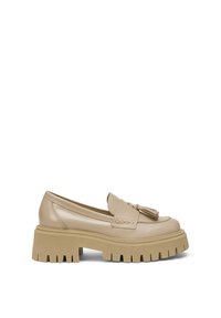 Mocassin en cuir beige avec semelle épaisse à rainures et détail pompon sur le dessus, style slip-on, accents de couture minimalistes.