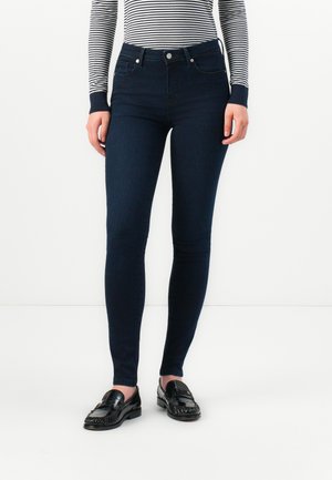 Mørkeblå skinny jeans med høj talje, der har en lukning foran med knap, diskret syning og en glat, let strækbar tekstur.