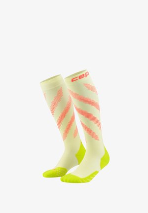 Knee-high compression socks in pale yellow with coral diagonal stripes and bright yellow heel and toe sections, featuring "cep" branding at the top.