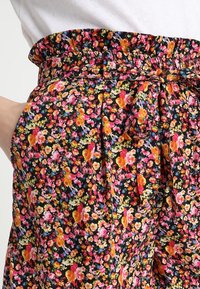 Blommönstrade shorts med svart bakgrund och färgglada blommor i rosa, orange och blått. Elastisk midja med knytal.