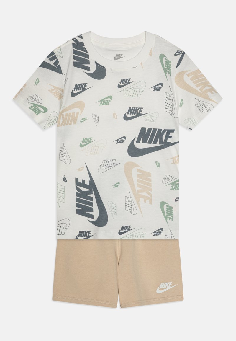 Marškinėliai ir šortai rinkinys, susidedantis iš šviesiai pilkų marškinėlių su daugiakomponentėmis Nike logotipais ir smėlio spalvos šortų su mažuoju logotipu ant krašto.