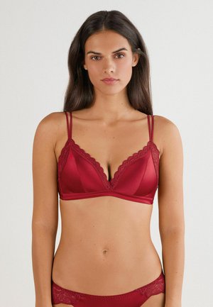 Soutien-gorge bordeaux avec une finition satinée lisse, des bonnets triangulaires, des bordures en dentelle et des bretelles fines et réglables. Associé à un dessous en dentelle assorti.