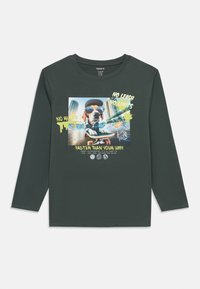 Μακρυμάνικη μπλούζα σε σκούρο πράσινο χρώμα από βαμβάκι με γραφικό σχέδιο που απεικονίζει έναν σκύλο πάνω σε σκέιτμπορντ, διακοσμημένη με πολύχρωμο κείμενο και σχέδια.