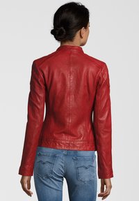 Rote Lederjacke mit taillierter Passform, die dezente Stickdetails und einen hohen Kragen aufweist. Über blauen Jeans getragen, von hinten betrachtet.