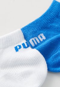 Puma gležnjači s split oblikovanjem: bel del z modrimi akcenti in moder del z belim blagovnim znakom. Material se zdi pleten.