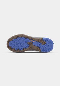 Semelle de chaussure de trail en caoutchouc brun et bleu, texturée pour une prise en main, avec des crampons multidirectionnels pour la traction et la durabilité.
