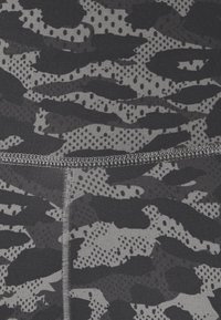 Leggings a vita alta caratterizzati da un motivo camouflage grigio e nero con punti testurizzati e aree lisce a contrasto. Dettagli delle cuciture piatte visibili.