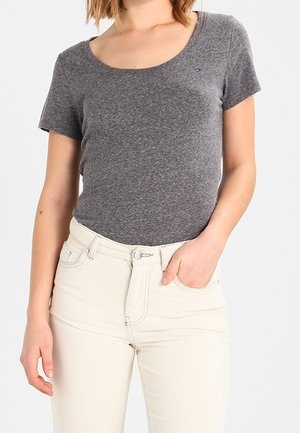 Grijs kortärmlig top van katoenmix met een ronde hals, gecombineerd met witte high-waisted jeans met knoopsluiting en zakken.
