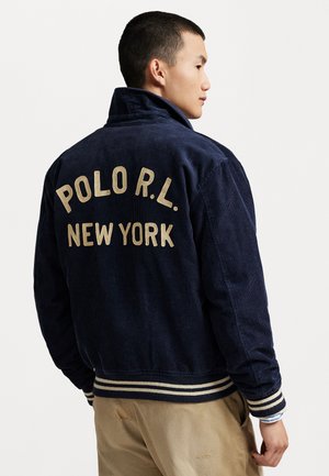 Navy corduroy jacket featuring "POLO R.L. NEW YORK" embroidered in gold on the back, with striped ribbed cuffs and collar.
