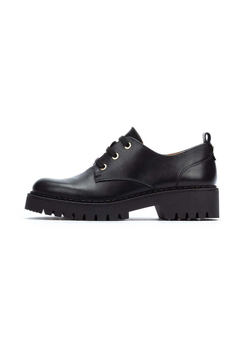 Chaussure en cuir noir à lacets avec un bout arrondi, œillets en or et une semelle en caoutchouc épaisse et texturée. Design minimaliste avec une languette au talon.