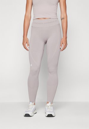 Light grey Under Armour leggings with a high waistband, seamless design, and textured fabric. Paired with white athletic shoes.