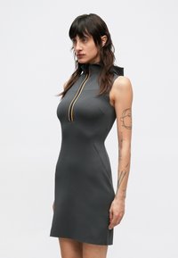 Vestido cinzento escuro sem mangas com gola alta, com fecho de correr frontal e detalhe em laranja. Material liso e justo ao corpo, com costuras mínimas.
