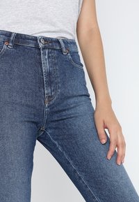 Högmidjade blå jeans av denim, med slim fit, framfickor och kopparfärgad hårdvara med minimal slitage.