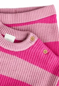 Randig stickad tröja i mjuka rosa nyanser, med ribbad textur, träknappdetaljer vid axeln och en rundad halsringning.