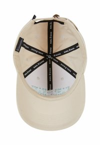 Beige cap with a curved visor, interior featuring black straps with "KARL KANI" branding, and a textured lining.