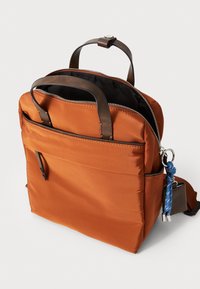 Borsa da viaggio arancione in tessuto con manici e dettagli in pelle marrone. Caratterizzata da una chiusura superiore con zip, tasca frontale e una tracolla staccabile.