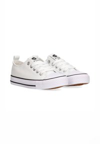 Zapatillas de lona blancas con puntera redonda, suela blanca gruesa, detalle de franja negra y ojales de metal para los cordones. Suela de goma para mayor tracción.