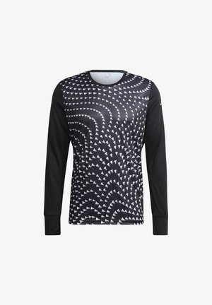 Man rennend in een zwart, geometrisch patroon lang shirt, zwarte korte broek, witte sokken en zwarte hardloopschoenen op een witte achtergrond.