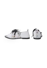 Witte casual schoenen met een gemusterde stof met bloemenaccenten, een contrasterende zwarte zool en zwarte ribbonden met een stippenstructuur.