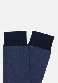 Námořnické modré ponožky s texturovaným povrchem, se žebrovaným lemem. Design zahrnuje melírovaný vzor po celé ploše.