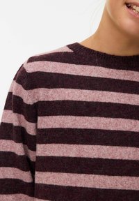 Knit pulover z debelimi vodoravnimi črtami v temno burgundski in svetlo roza barvi. Okrogla izrezana ovratnica in mehak tekstur, z rahlo puhasto strukturo.