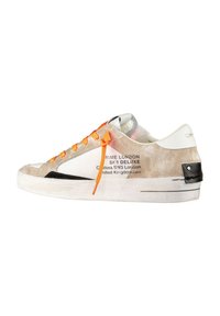 Zapatilla blanca con acentos en beige y negro. Presenta cordones naranjas y detalles impresos en el lateral. Parte superior texturizada con una suela lisa.