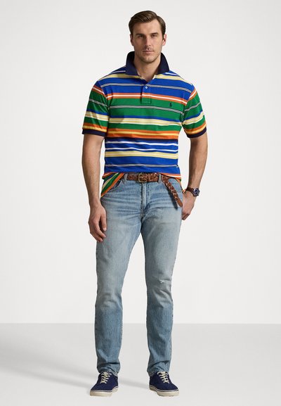Striped polo shirt in blue, green, orange, and white with a navy collar. Worn with light blue jeans and dark sneakers. Belt with a woven pattern.