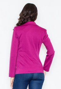 Magenta dopasowana marynarka z wyciętym kołnierzem i długimi rękawami. Gładka tekstura, dopasowany kształt oraz czyste linie, zestawiona z ciemnymi dżinsami.