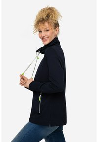 Chaqueta de forro polar navy con cuello alto, cordón ajustable y bolsillo lateral con cremallera. Presenta detalles en hardware verde contrastante.